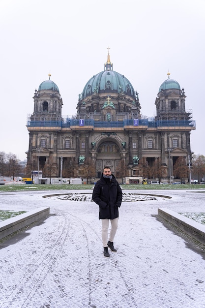 Giovane turista maschio che cammina nel parco di fronte alla Cattedrale di Berlino con neve dappertutto