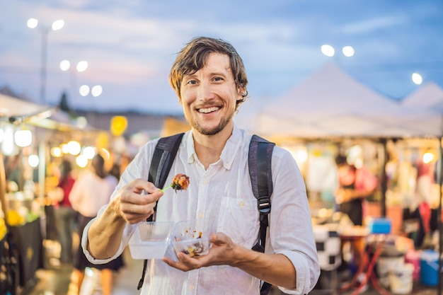 Giovane turista sul mercato alimentare asiatico Walking Street