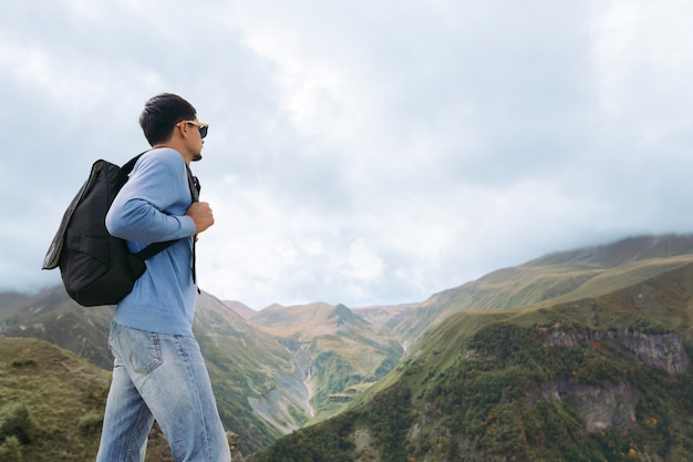 Giovane turista uomo con uno zaino sullo sfondo delle montagne del Caucaso, in Georgia in una giornata nebbiosa. copia spazio