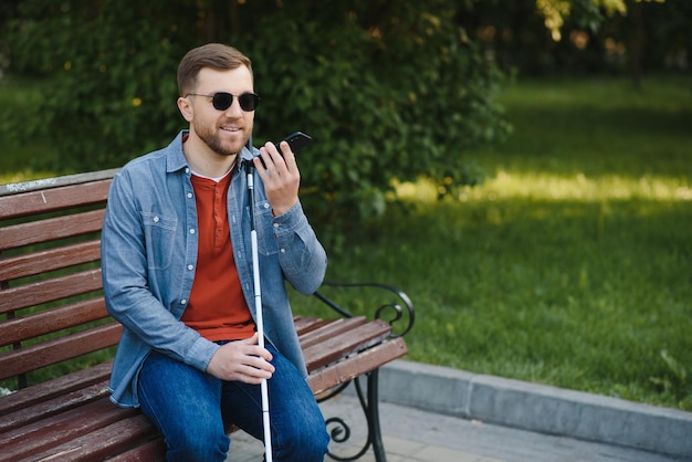 Giovane uomo accecato usando il telefono e inviando un messaggio vocale