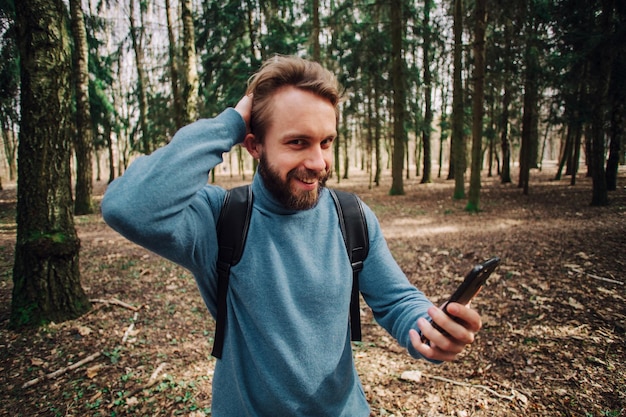 Giovane uomo adulto che parla al telefono in piedi nella foresta