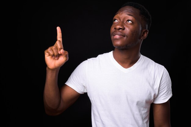 giovane uomo africano bello con i capelli afro contro il muro nero