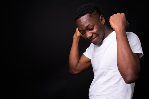 giovane uomo africano bello con i capelli afro contro il muro nero