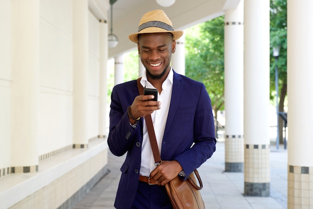 Giovane uomo africano che cammina con cellulare e borsa