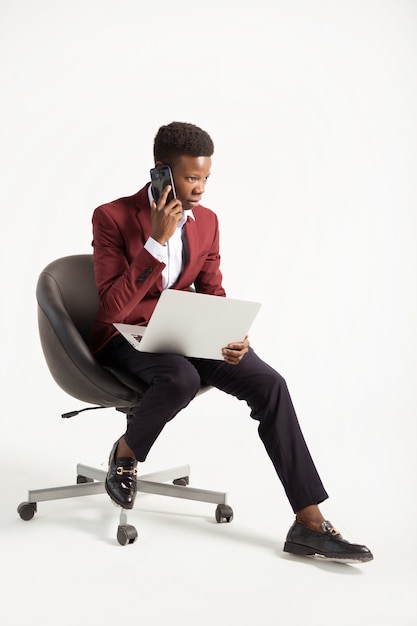 Giovane uomo africano in un vestito con un computer portatile