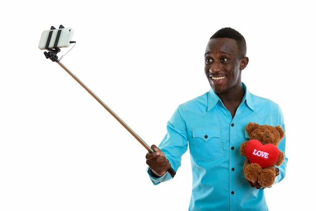 Giovane uomo africano nero felice sorridente e tenendo l'orsacchiotto