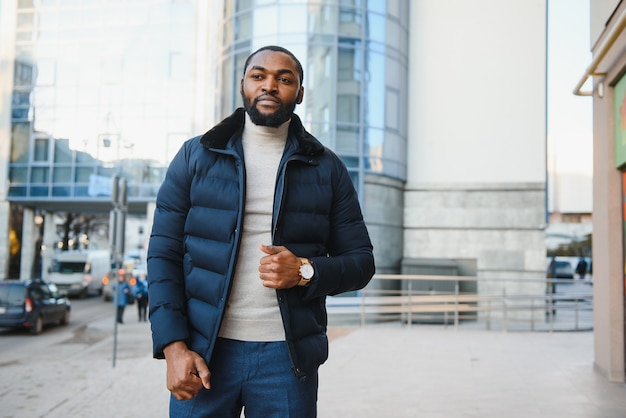 Giovane uomo afro-americano in vestiti alla moda che propongono all'aperto