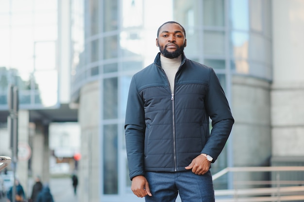 Giovane uomo afro-americano in vestiti alla moda che propongono all'aperto