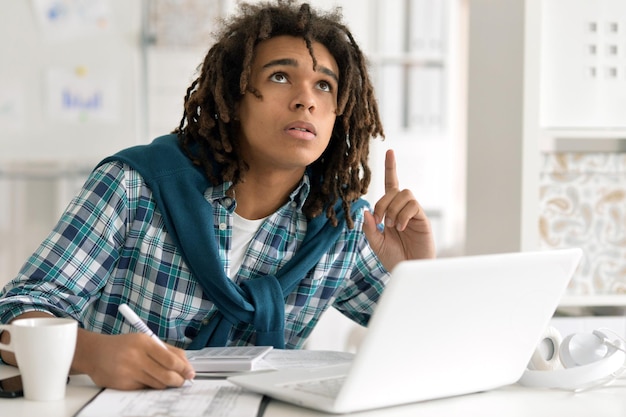 Giovane uomo afro che lavora in ufficio, usando il laptop