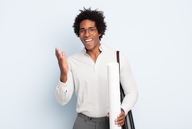 Giovane uomo afro nero che si sente felice, sorpreso e allegro, sorridente con atteggiamento positivo, realizzando una soluzione o un'idea