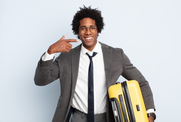 Giovane uomo afro nero che sorride con sicurezza indicando il proprio ampio sorriso