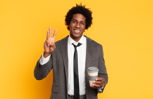 Giovane uomo afro nero sorridente e guardando amichevole, mostrando il numero tre o terzo con la mano in avanti, il conto alla rovescia