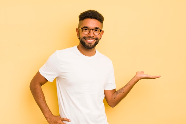 Giovane uomo afro sorridente sentirsi fiducioso di successo e felice che mostra il concetto o l'idea sullo spazio della copia sul lato