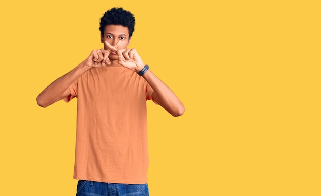 Giovane uomo afroamericano che indossa abiti casual espressione di rifiuto incrociando le dita facendo segno negativo