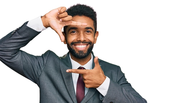 Giovane uomo afroamericano che indossa abiti da lavoro sorridente facendo cornice con le mani e le dita con la creatività del viso felice e il concetto di fotografia