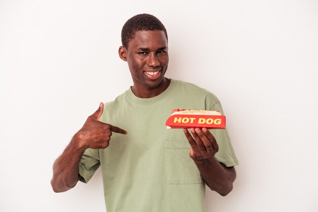 Giovane uomo afroamericano che mangia un hot dog isolato su sfondo bianco persona che indica a mano uno spazio copia camicia, orgoglioso e fiducioso