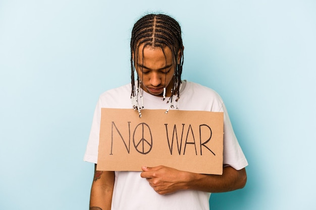 Giovane uomo afroamericano che non tiene cartello di guerra isolato su sfondo blu