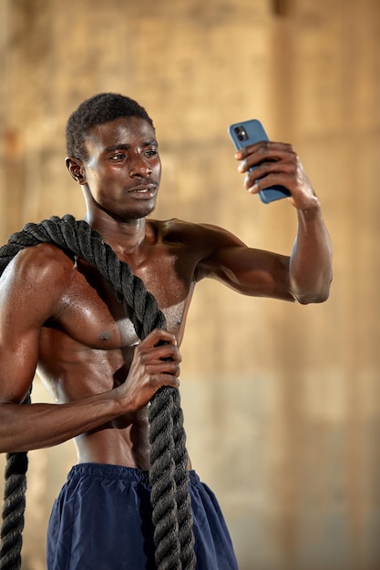 Giovane uomo afroamericano che parla sul suo smartphone all'aperto giovane atleta maschio nero rilassarsi dopo