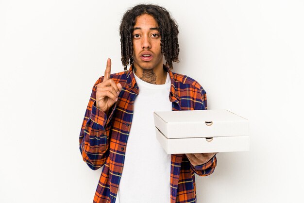 Giovane uomo afroamericano che tiene pizze isolate su sfondo blu con qualche grande idea di creatività