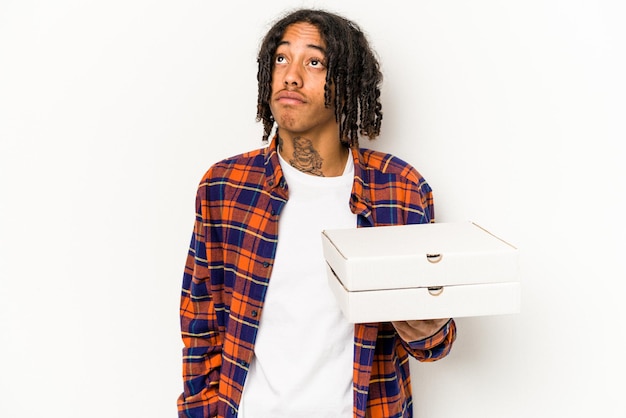 Giovane uomo afroamericano che tiene pizze isolate su sfondo blu sognando di raggiungere obiettivi e scopi