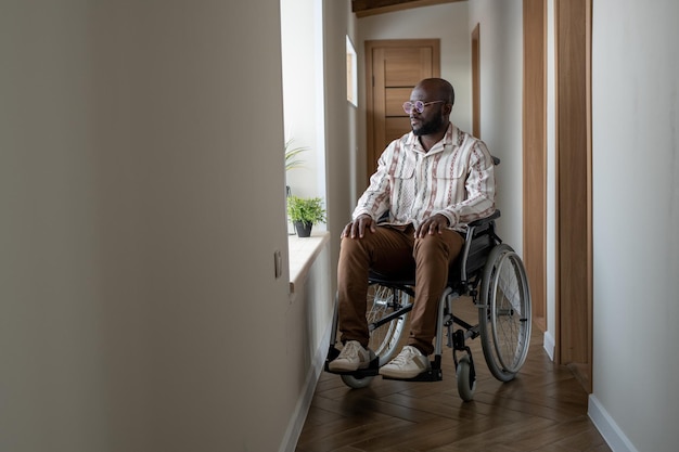 Giovane uomo afroamericano con disabilità che guarda attraverso la finestra