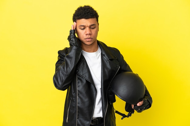 Giovane uomo afroamericano con un casco da motociclista isolato su sfondo giallo con mal di testa