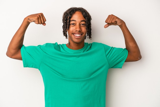 Giovane uomo afroamericano isolato su sfondo bianco che mostra gesto di forza con le braccia, simbolo del potere femminile