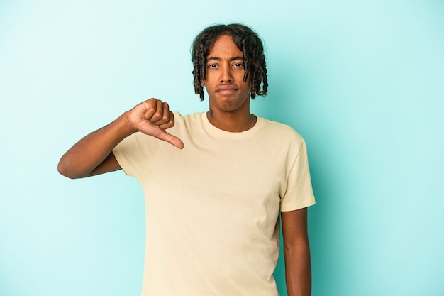 Giovane uomo afroamericano isolato su sfondo blu che mostra pollice verso il basso, concetto di delusione.