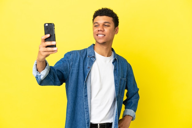 Giovane uomo afroamericano isolato su sfondo giallo facendo un selfie