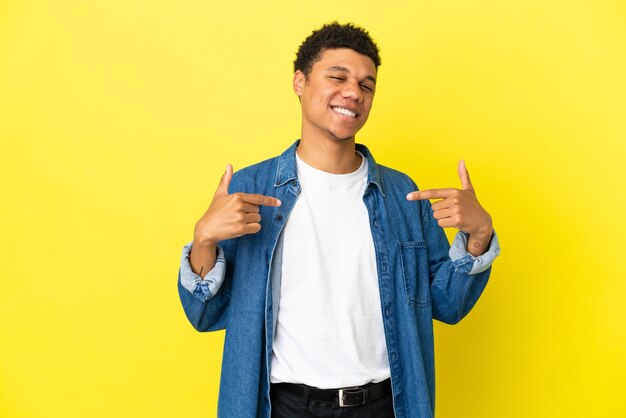 Giovane uomo afroamericano isolato su sfondo giallo orgoglioso e soddisfatto di sé