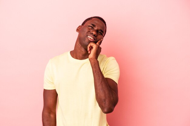 Giovane uomo afroamericano isolato su sfondo rosa che piange, insoddisfatto di qualcosa, agonia e concetto di confusione.