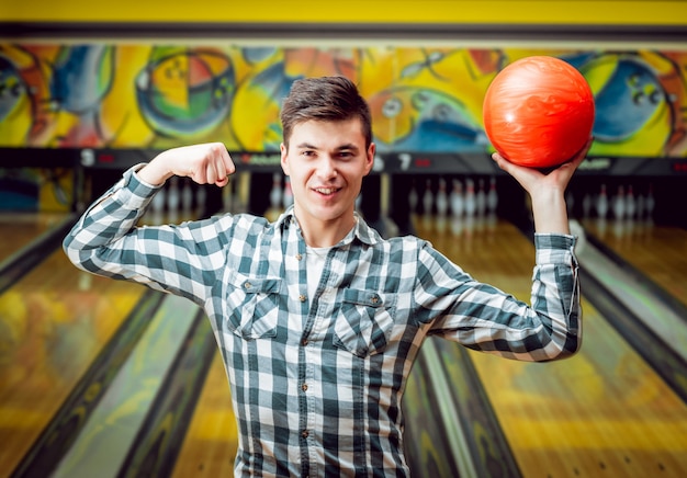 Giovane uomo al bowling con la palla.