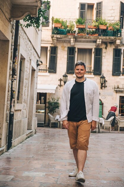 Giovane uomo alla moda che cammina per la strada stretta di Kotor Montenegro