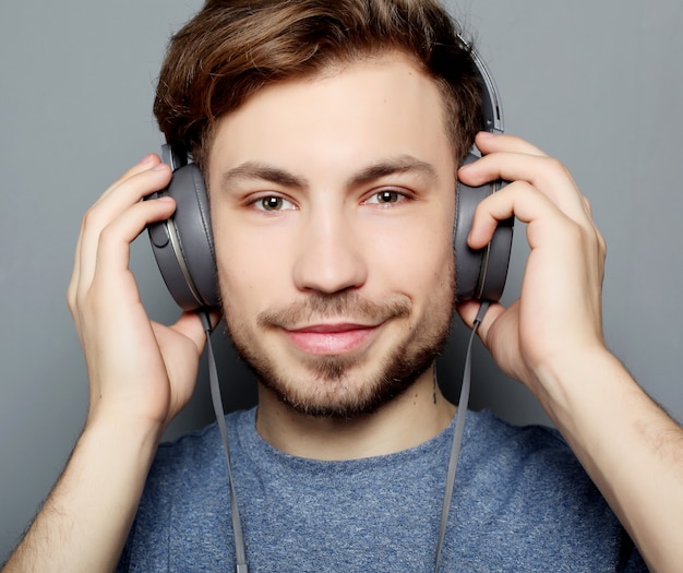 Giovane uomo alla moda felice che regola le sue cuffie