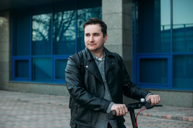 Giovane uomo alla moda in strada urbana utilizzando scooter elettrico