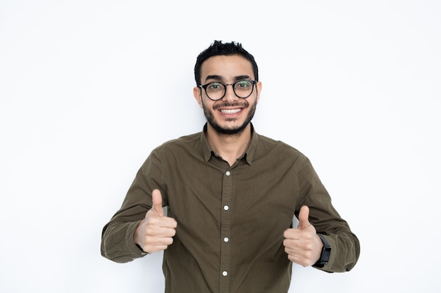 Giovane uomo allegro con un sorriso a trentadue denti che mostra i pollici in su in isolamento