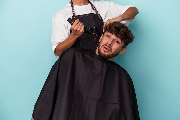 Giovane uomo arabo pronto a tagliarsi i capelli isolato su sfondo blu