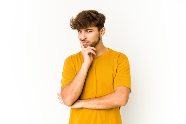 Giovane uomo arabo su uno spazio bianco contemplando, pianificando una strategia, pensando al modo di fare impresa.