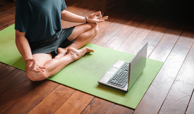 Giovane uomo asiatico allenatore internet video formazione online istruttore di yoga moderno schermo portatile meditare