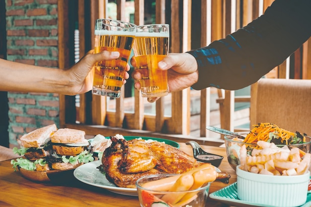 Giovane uomo asiatico bere bicchieri di birra e clink felice mentre godendo la festa a casa