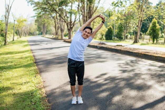 Giovane uomo asiatico che fa esercizio di stretching preparandosi per correre nella natura Stile di vita sano