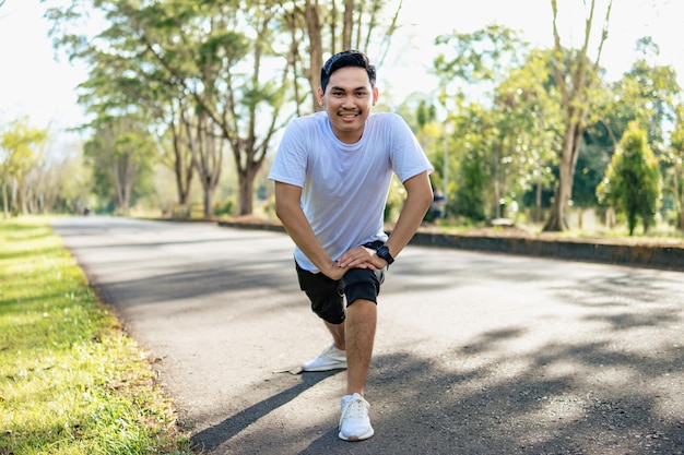 Giovane uomo asiatico che fa esercizio di stretching preparandosi per correre nella natura Stile di vita sano