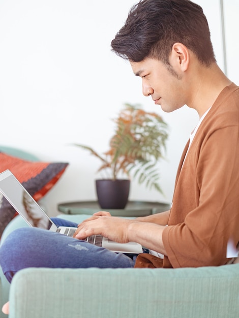 Giovane uomo asiatico che indossa abiti casual e usa il laptop