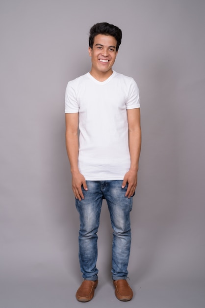 giovane uomo asiatico che indossa camicia bianca contro il muro grigio