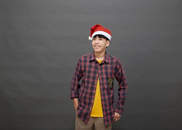 Giovane uomo asiatico che indossa il cappello di Natale su studio shot, isolato su sfondo grigio