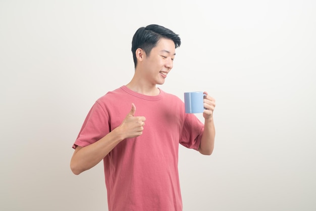 giovane uomo asiatico che tiene una tazza di caffè con la faccia sorridente su sfondo bianco