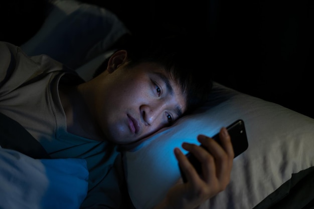 Giovane uomo asiatico che utilizza smartphone di notte