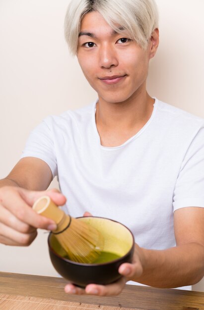 Giovane uomo asiatico con il tè di matcha in una tabella