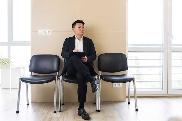 giovane uomo asiatico di successo in attesa di un colloquio di lavoro nella sala d'attesa del centro uffici s