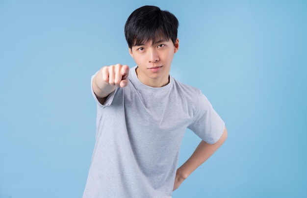 Giovane uomo asiatico in posa su sfondo blu